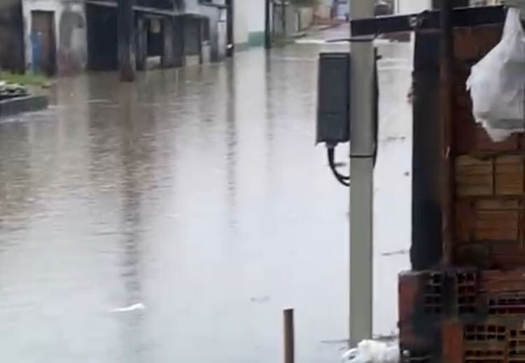 Moradores caminham por rua alagada na Comunidade da Sharp após forte chuva em Manaus