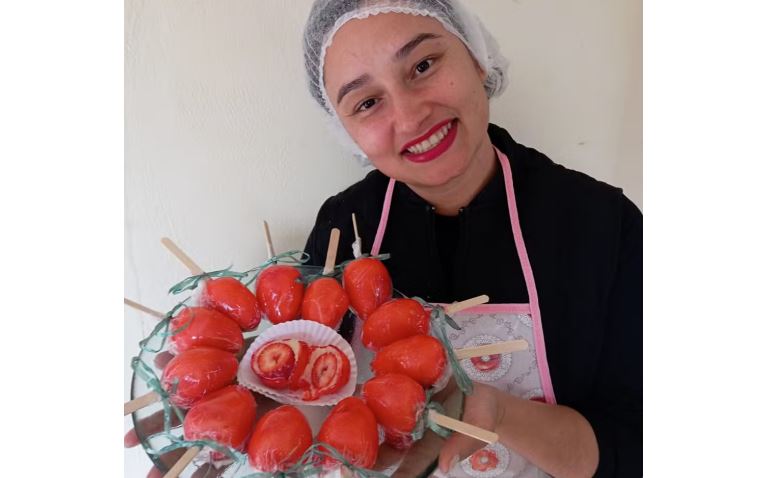 Confeiteira Cláudia Nicoleti segura morango do amor em Senador Amaral