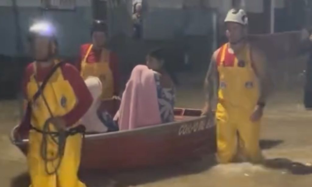Bombeiros usam bote para resgatar moradores de rua alagada por chuva em Manaus