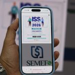 Mão segura celular em página do Manaus Atende Digital que garante desconto de 2% para pagamento do ISS Fixo
